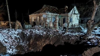 Local residents walk near a house damaged by a Russian missile strike. (REUTERS)