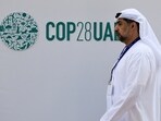 A delegate walks past a logo of the COP28 climate summit in Dubai, United Arab Emirates.