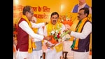 Madhya Pradesh’s new chief minstMohan Yadav being greeted by outgoing CM Shivraj Singh Chouhan and BJP state president VD Sharma in Bhopal on Monday. (PTI)