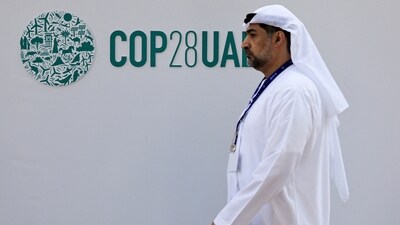 A delegate walks past a logo of the COP28 climate summit in Dubai, United Arab Emirates. (REUTERS)