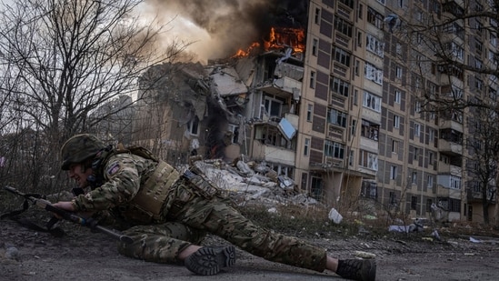 Russia-Ukraine War: A Ukrainian police officer takes cover in front of a burning building that was hit in a Russian airstrike in Avdiivka, Ukraine. (AP)