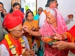 Jasmani Devi, mother of Chhattisgarh Chief Minister-designate Vishnu Deo Sai, applies 'tilak' on his forehead before his swearing-in ceremony, in Raipur.