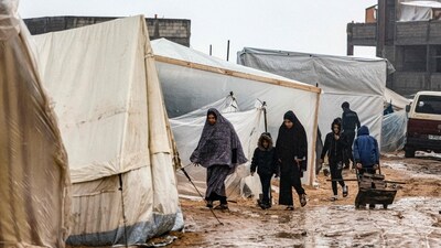 Israel-Hamas War: Palestinians walk under the rain at a camp for displaced people in Rafah, in the southern Gaza Strip. (AFP) Israel-Hamas War: Palestinians walk under the rain at a camp for displaced people in Rafah, in the southern Gaza Strip. (AFP)