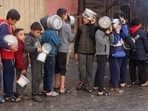 Palestinian children hold pots as they queue to receive food cooked by a charity kitchen, amid shortages in food supplies. 