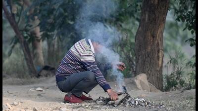 A man starts a wood fire to keep himself warm in Noida. (Sunil Ghosh/HT Photo) A man starts a wood fire to keep himself warm in Noida. (Sunil Ghosh/HT Photo)