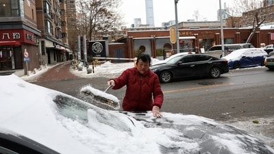 A woman brushes off snow from a car window in Beijing following the recent snowfall. In Liaoning province's Shenyang city, extensive snow removal operations involving thousands of workers and machines were undertaken. (REUTERS)