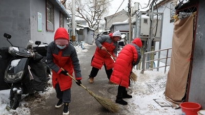In Beijing, community workers clear snow-covered paths in hutong alleys after the recent snowfall. Shanghai witnessed temporary suspensions in ferries and buses due to the city's first cold wave alert, anticipating temperatures as low as minus 6 degrees Celsius. (REUTERS)