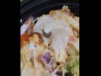 The image shows a snail in a bowl of salad. The image shows a snail in a bowl of salad.
