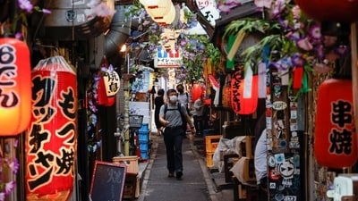 Japan Flu Cases: People wearing protective masks walk at a Japanese Izakaya pub alley, amid the coronavirus disease (Covid-19) outbreak, in Tokyo. (Reuters)