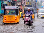 Commuters make their way amid rains on a waterlogged road in Chennai.