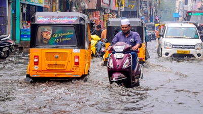 Commuters make their way amid rains on a waterlogged road in Chennai. (PTI) Commuters make their way amid rains on a waterlogged road in Chennai. (PTI)