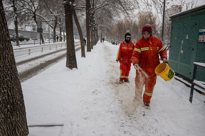 Workers scatter salt over a snow covered sidewalk in Beijing, China. (Bloomberg)