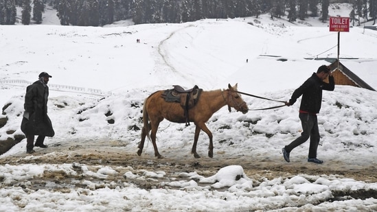 People seen walking through snow covered roads in Jammu and Kashmir on Sunday. The Gulmarg ski resort in north Kashmir's Baramulla district registered a low temperature of minus 2.8 degrees Celsius, compared to the previous night's minus 3.4 degrees Celsius. The current temperature at the resort is 1.4 degrees Celsius above the normal range.(ANI)