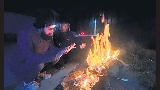 Residents warming themselves during a chilly evening in Srinagar. (Waseem Andrabi/HT)