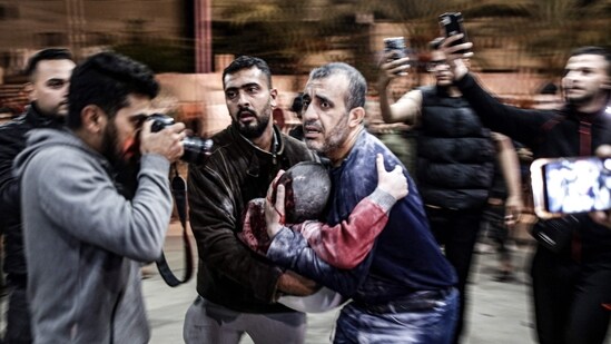 Israel-Hamas War: A man carrying a child, injured following Israeli bombardment, arrives to Nasser hospital in Khan Yunis in the southern Gaza Strip. (AFP)