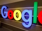 An illuminated Google logo is seen inside an office building