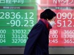 A person walks near an electronic stock board showing Japan's Nikkei 225, left,  and New York Dow indexes at a securities firm Thursday, Dec. 14, 2023, in Tokyo.  Shares are mostly higher in Asia after a powerful rally across Wall Street sent the Dow Jones Industrial Average to a record high as the Federal Reserve indicated that interest rate cuts are likely next year.(AP Photo/Eugene Hoshiko)