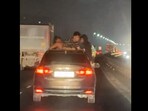 The image shows a group of men dancing in a moving car. The image shows a group of men dancing in a moving car.