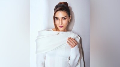Coming to Kriti's outfit, the white dress features full-length sleeves, a bateau neckline, a shawl attached to the neck forming an ankle-length drape, a figure-hugging silhouette, an A-line skirt, a midi-length hem, a front slit, and padded shoulders. She styled the ensemble with purple high-heeled stilettos.&nbsp; (Instagram)