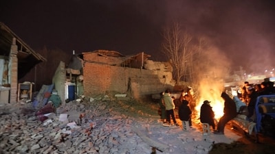 Residents keep warm around a fire in the early morning after an earthquake in Dahejia, Jishishan County, in northwest China's Gansu province. (AFP)