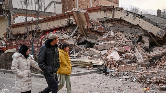 People walk past a collapsed building after an earthquake in Dahejia, Jishishan County in northwest China's Gansu province People walk past a collapsed building after an earthquake in Dahejia, Jishishan County in northwest China's Gansu province