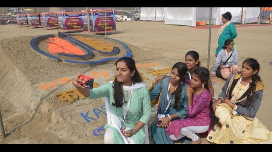 Guests being welcomed at Sangam and posing for photographs at the sand art created in their honour. (HT)