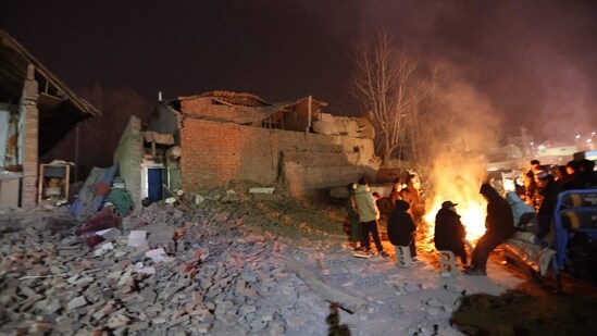 Residents keep warm around a fire in the early morning after an earthquake in Dahejia, Jishishan County, in northwest China's Gansu province. According to local meteorological authorities, the daily low temperature in Jishishan is reported to climb minus 10 degrees Celsius on Tuesday.(AFP)