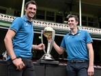 Australian cricketers Mitchell Starc (L) and team captain Pat Cummins pose with the ICC Men's Cricket World Cup 2023 Trophy 