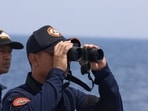 A Philippine Coast Guard personnel looks through a binocular while conducting a resupply mission for Filipino troops stationed at a grounded warship in the South China Sea.