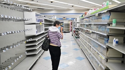 A woman browses through what items remain on near empty shelves at a Rite Aid store in California. (AFP) A woman browses through what items remain on near empty shelves at a Rite Aid store in California. (AFP)