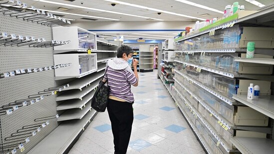 A woman browses through what items remain on near empty shelves at a Rite Aid store in California. (AFP)
