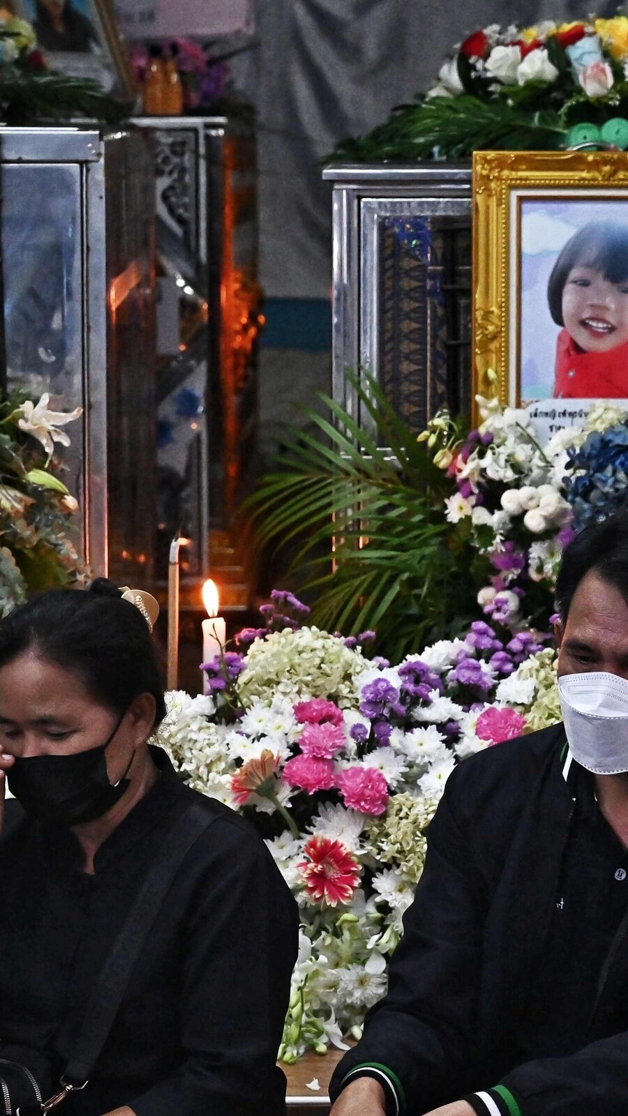 Relatives sit in front of the coffins of victims of the nursery mass shooting in Thailand.