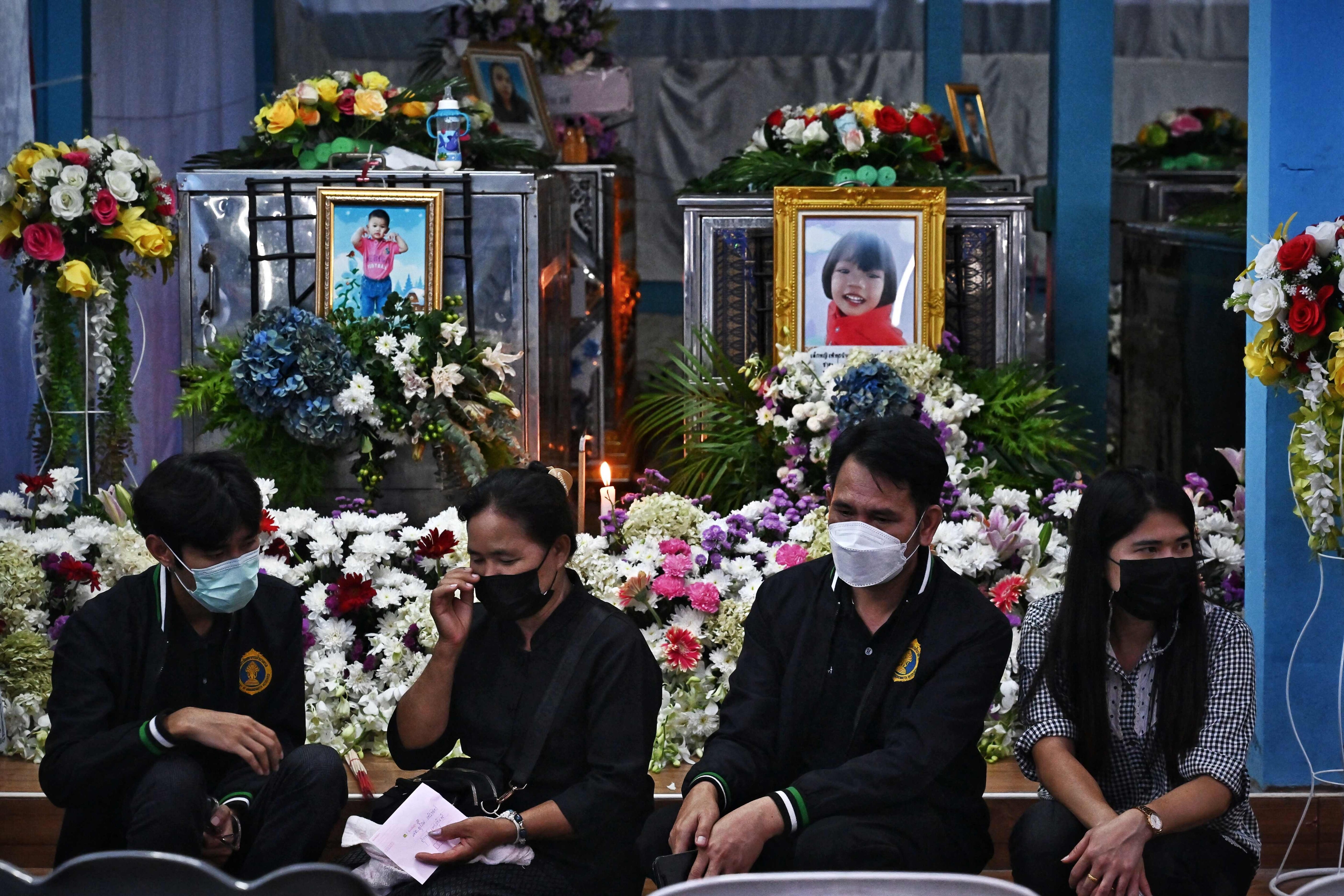 Relatives sit in front of the coffins of victims of the nursery mass shooting in Thailand.