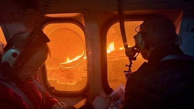 A helicopter flies near a volcano spewing lava and smoke as it erupts near Grindavik, Iceland. (via REUTERS)