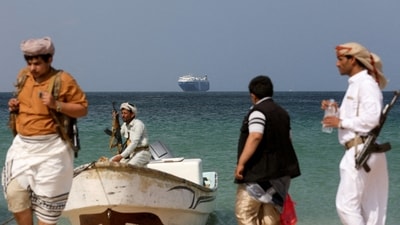 Armed men stand on the beach as the Galaxy Leader commercial ship, seized by Yemen's Houthis last month, is anchored off the coast of al-Salif in Yemen on December 5. (Reuters)