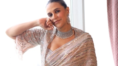 Neha Dhupia in a dusty pink embellished saree and a matching blouse and cape jacket by Disha Arora, accessorised with a diamond choker with pearls by Naulakha Jewellers.