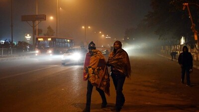 People wrapped in a blanket walking along the road on a cold and foggy winter morning at South West Delhi in Kapashera near MCD office in New Delhi. (HT Photo/Praveen Kumar) People wrapped in a blanket walking along the road on a cold and foggy winter morning at South West Delhi in Kapashera near MCD office in New Delhi. (HT Photo/Praveen Kumar)