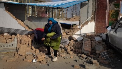 A woman collects clothes from her damaged home after the earthquake in Jishishan county, in northwest China's Gansu province.&nbsp; (AP)