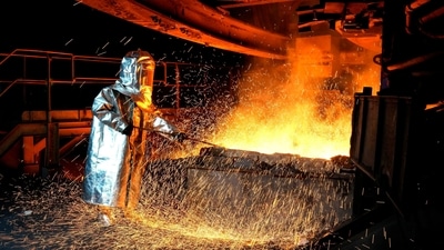 A worker in a protective suit pokes a metal rod to tap slag from a smelting furnace at a nickel processing plant in Indonesia (Representational picture) (AP) A worker in a protective suit pokes a metal rod to tap slag from a smelting furnace at a nickel processing plant in Indonesia (Representational picture) (AP)