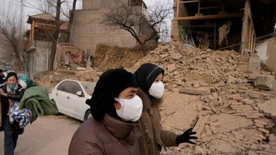 Residents pass by a house that crumbled after an earthquake in Dahejia town in northwestern China's Gansu province. (AP)