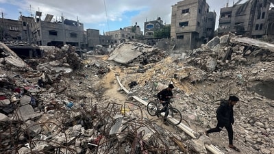 Palestinians walk among the rubble, as they inspect houses destroyed in Israeli strikes. (Reuters)