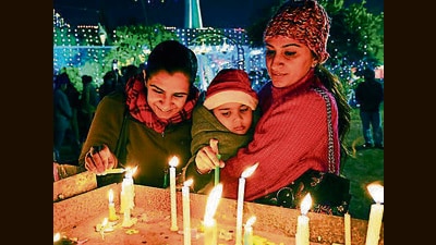 SANTA CLAUS IS COMING TO TOWN: People light a candle on Christmas Eve at the church in Sector 19, Chandigarh, on Sunday. (Keshav Singh/ht)