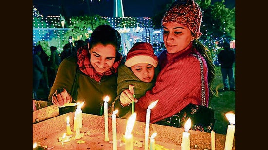 SANTA CLAUS IS COMING TO TOWN: People light a candle on Christmas Eve at the church in Sector 19, Chandigarh, on Sunday. (Keshav Singh/ht)