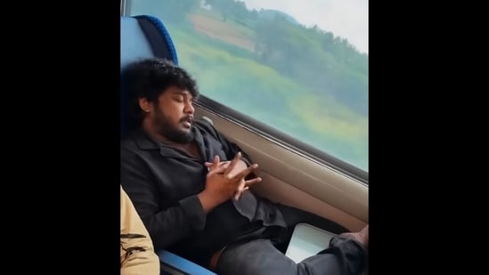 Passenger travelling on Vande Bharat train with his foot on snacks tray. (YouTube/@AarifsMindVoice)