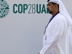 A delegate walks past a logo of the COP28 climate summit in Dubai, United Arab Emirates.