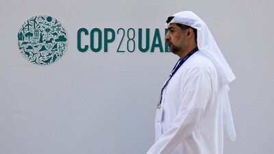 A delegate walks past a logo of the COP28 climate summit in Dubai, United Arab Emirates. (REUTERS)