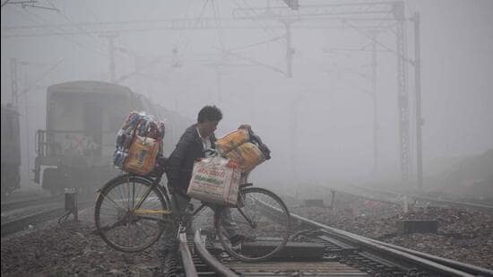 A man with his cycle crosses the railway tracks amid dense fog, in Prayagraj, on Thursday. (ANI)