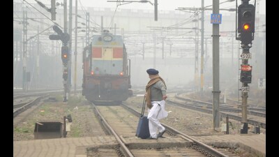 A passenger crosses railway tracks on a cold and foggy winter day, near a railway station in Amritsar. (PTI)