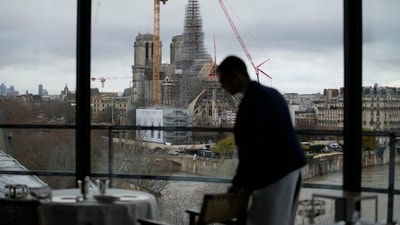 A waiter prepares tables at La Tour d'Argent restaurant in Paris, with Notre Dame cathedral in background, Wednesday, Dec. 13, 2023. The Tour d'Argent, which claims to be the oldest restaurant in the French capital, has a front-row view of the renaissance of Notre Dame Cathedral as artisans prepare the fire-ravaged monument for reopening next year. The high-end restaurant, which helped inspire the movie "Ratatouille,'' recently reopened after its own renovation that preserved traditions while adapting to the 21st century. It will also overlook the opening ceremony of the Paris Olympics on July 26, 2024. (AP Photo/Christophe Ena) A waiter prepares tables at La Tour d'Argent restaurant in Paris, with Notre Dame cathedral in background, Wednesday, Dec. 13, 2023. The Tour d'Argent, which claims to be the oldest restaurant in the French capital, has a front-row view of the renaissance of Notre Dame Cathedral as artisans prepare the fire-ravaged monument for reopening next year. The high-end restaurant, which helped inspire the movie "Ratatouille,'' recently reopened after its own renovation that preserved traditions while adapting to the 21st century. It will also overlook the opening ceremony of the Paris Olympics on July 26, 2024. (AP Photo/Christophe Ena)