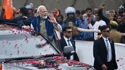 PM Modi is seen during a road show at Rampath in Ayodhya. Modi is accompanied by security guards as his cavalcade moves forward. The crowd cheers at him while the prime minister waves back. (HT Photo/Deepak Gupta)